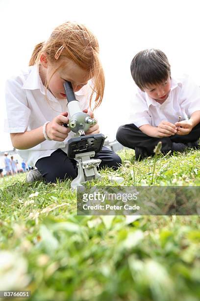 school girl looking through microscope - banbossy stock pictures, royalty-free photos & images