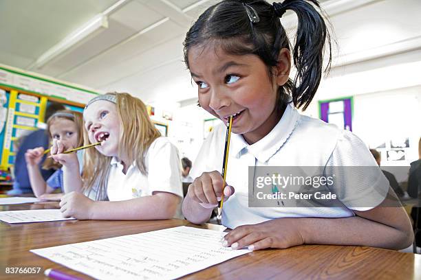 school girls writing in class - bijten stockfoto's en -beelden