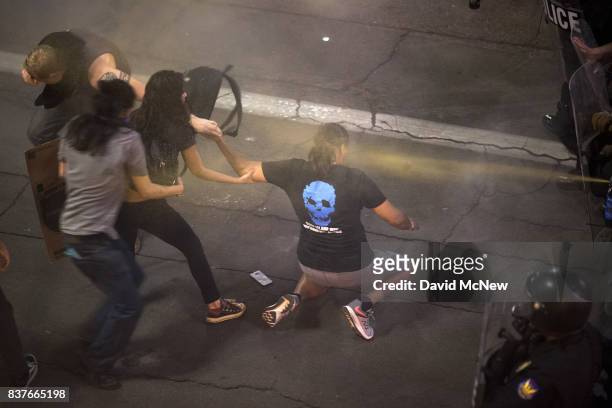 Demonstrators try to help a colleague as they are pepper sprayed repeatedly by advancing police officers after a rally by President Donald Trump at...