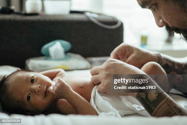 father changing baby boy (0-1 months) on bed - changing nappy stock pictures, royalty-free photos & images