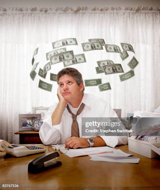 man paying bills surrounded by flying dollars - 50 dollars stock pictures, royalty-free photos & images