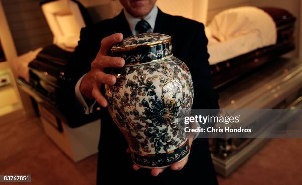 Funeral director Peter DeLuca, owner of Greenwich Village Funeral Home, holds a cremation urn in the showroom of his funeral parlor on November 20,...
