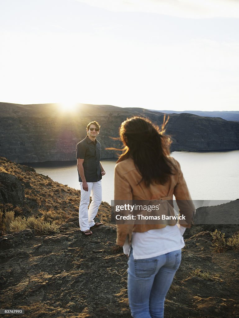 Couple standing above river gorge watching sunset