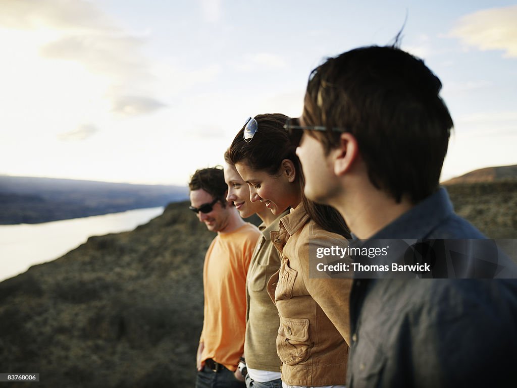 Group of four friends standing watching sunset