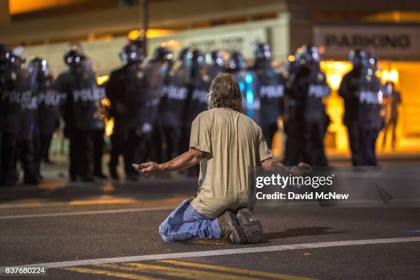 Man kneels in the street as police officers advance upon demonstrators after a rally by President Donald Trump at the Phoenix Convention Center on...