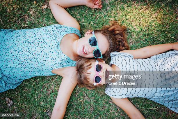 かわいい若い女の子自然の草の上に横たわると顔を作る - familys the lying game season two ストックフォトと画像