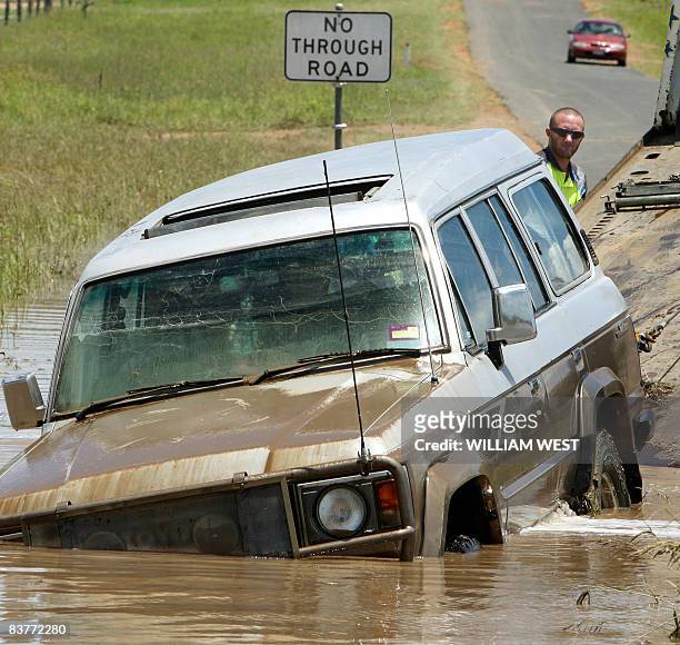 Tow truck operator tows a four-wheel drive vehicle from the floods to dry ground some 80 kilometres west of Brisbane, on November 21 as flash floods...