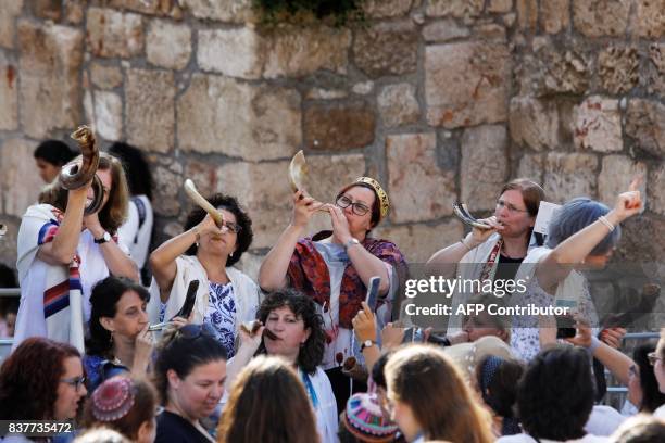 Members of the liberal Jewish religious group Women of the Wall, wearing skullcaps and traditional Jewish prayer shawls known as Tallit, blow Shofars...