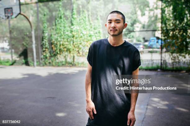 young athletic man standing in outdoor basketball court - males ストックフォトと画像