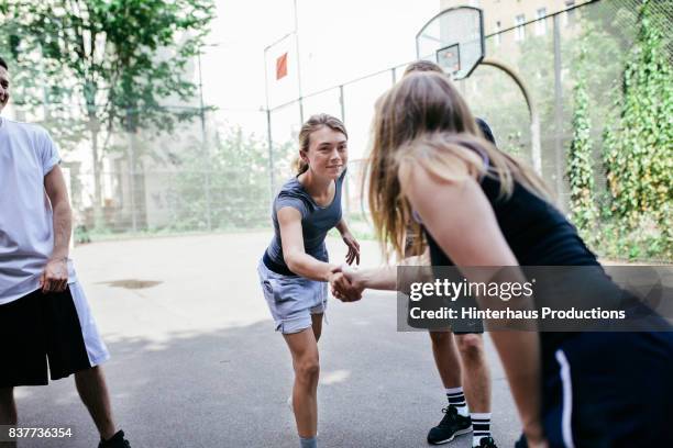 athletes shaking hands before friendly game of basketball outdoors - fairness stock-fotos und bilder