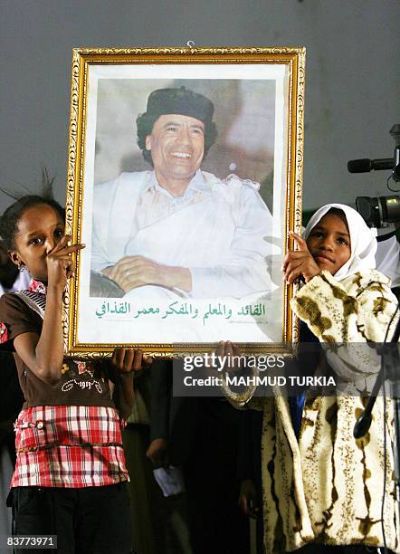 Libyan girls hold up a portrait of Libyan leader Moamer Kadhafi during an organised pro-government rally in the town of Kufra, 2000 kilometres from...