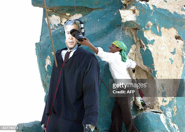An Iraqi Shiite Muslim uses a slipper to hit the face of an effigy of US President George W. Bush hung from the abstract statue that now stands in...