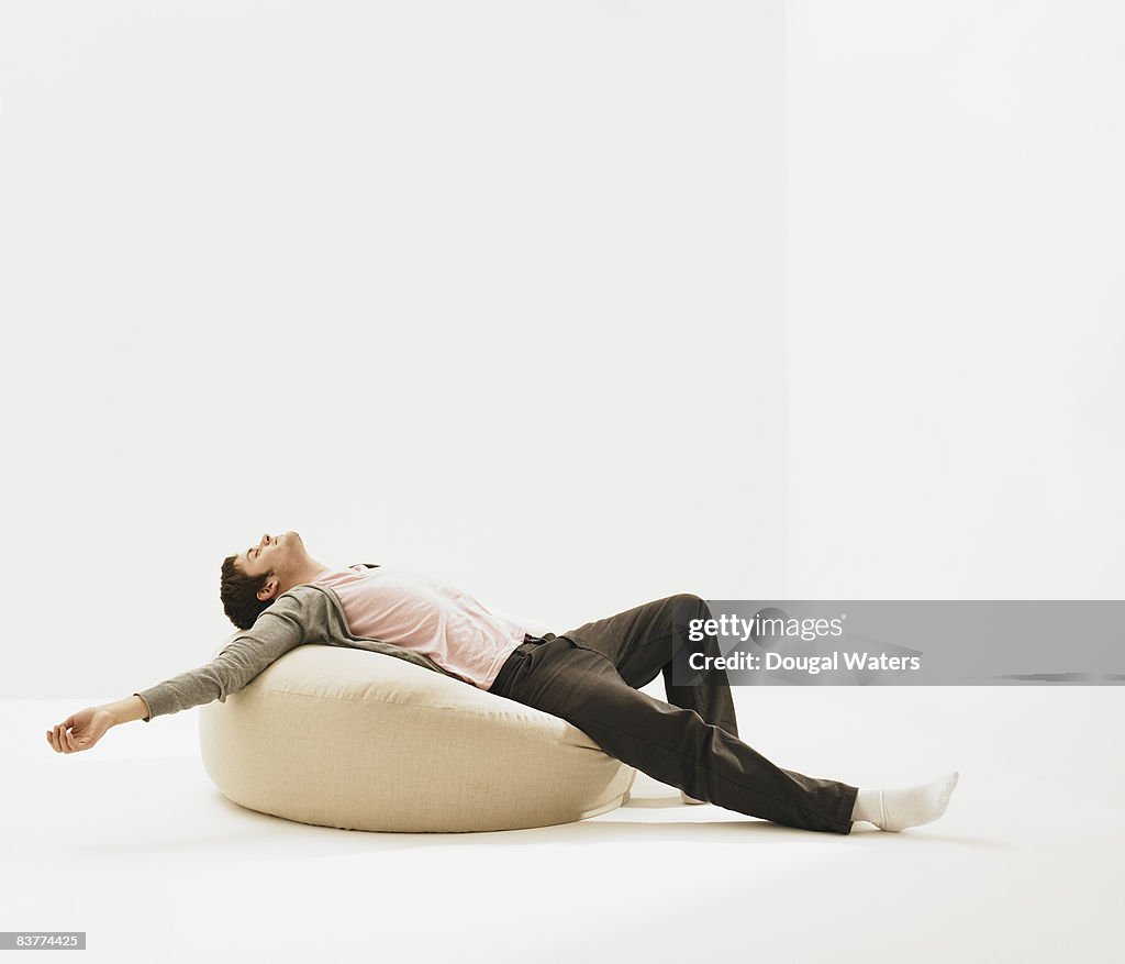 Young man laying on beanbag.