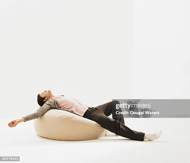 young man laying on beanbag. - beanbag photos et images de collection