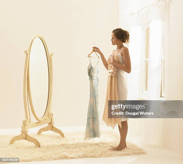young woman trying on dresses. - side view mirror stockfoto's en -beelden