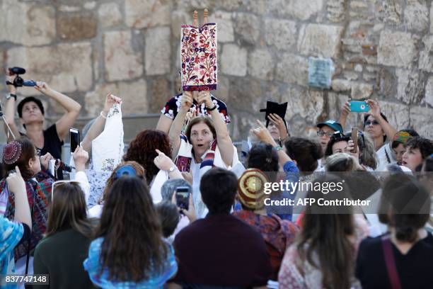 Members of the liberal Jewish religious group Women of the Wall, wearing skullcaps and traditional Jewish prayer shawls known as Tallit, hold up the...