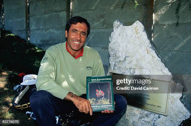 Spanish golfer Seve Ballesteros sitting next to a plaque commemorating one of his more remarkable shots, with a copy of his book 'Trouble-shooting',...