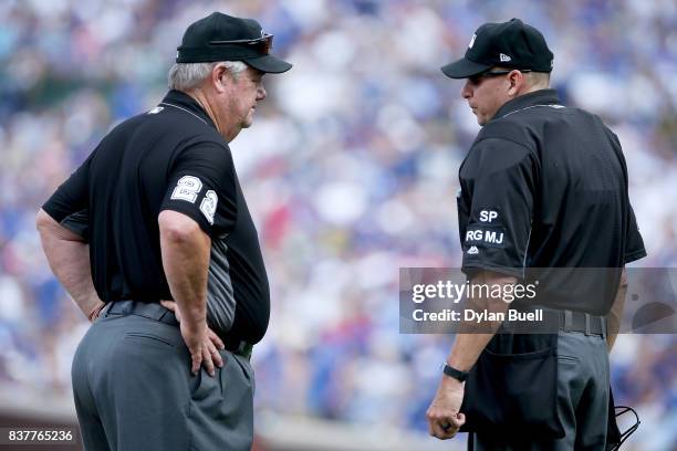 Umpires Joe West and Andy Fletcher meet meet during the game between the Chicago Cubs and Toronto Blue Jays at Wrigley Field on August 20, 2017 in...