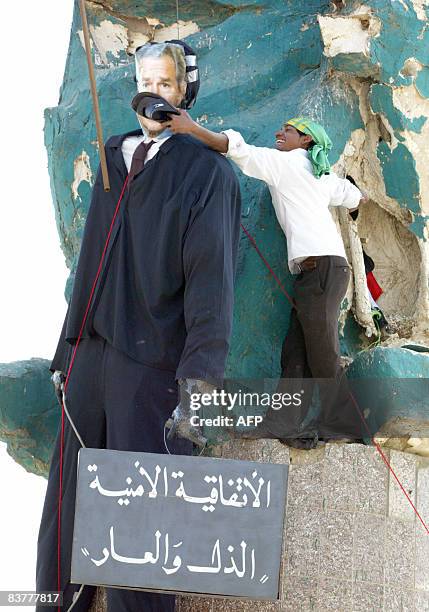 An Iraqi Shiite Muslim uses a slipper to hit the face of an effigy of US President George W. Bush and a sign that reads in Arabic, "The security...