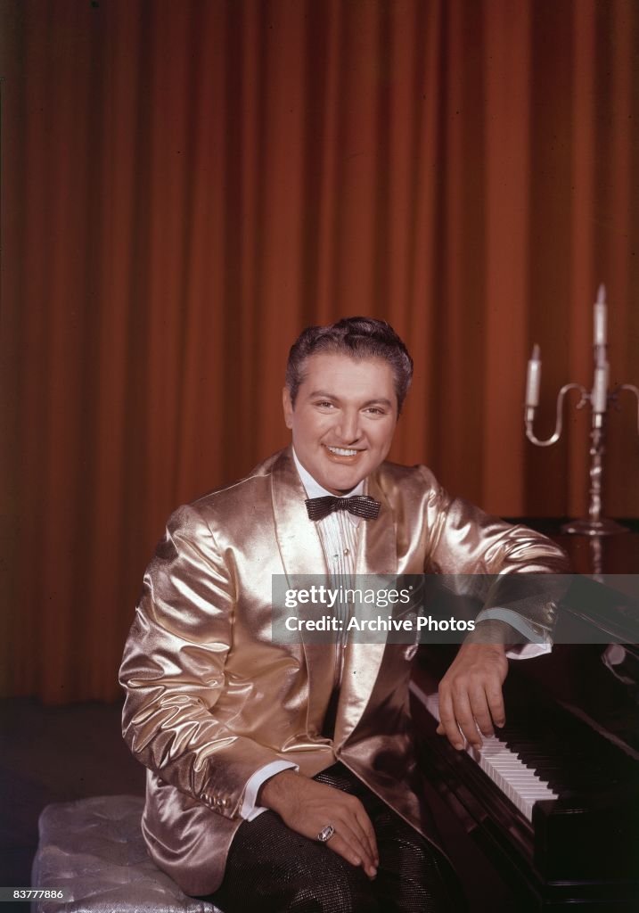 Liberace American pianist and entertainer Liberace sitting at a piano, wearing ...