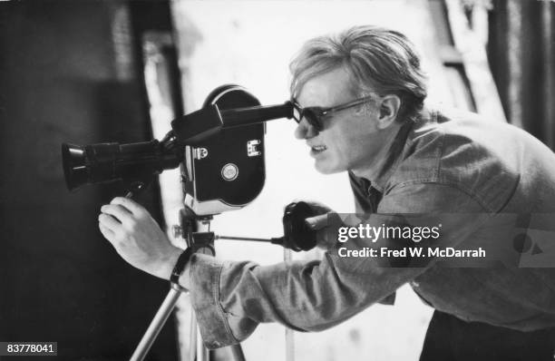 American pop artist Andy Warhol lines up a shot through the viewfinder of a 16mm Bolex camera during the filming of 'Taylor Mead's Ass' at his...