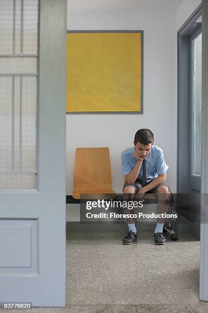 school boy sitting outside office - school punishment stockfoto's en -beelden