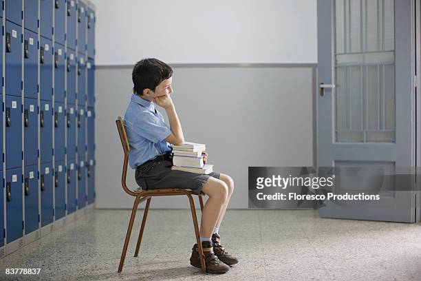 school boy sitting with books - school punishment photos et images de collection