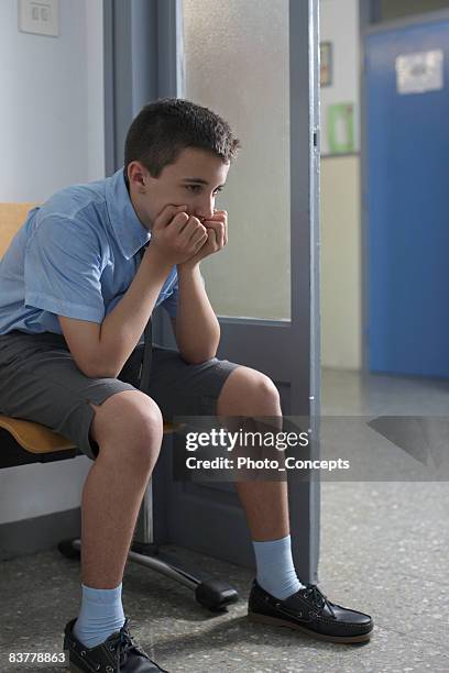 school boy sitting outside office - school punishment stockfoto's en -beelden