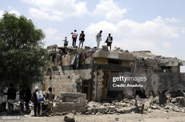 People gather around a heavily damaged building after Saudi-led coalition's air strikes over Arhab District of Sanaa, Yemen on August 23, 2017. At...