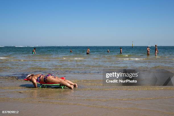 Melbourne, Australia, 18 march 2017. A woman lies on a chair in the water on saint Kilda beach. Melbourne is ranked as the worlds most liveable city...