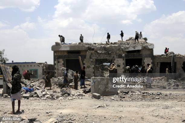 People gather around a heavily damaged building after Saudi-led coalition's air strikes over Arhab District of Sanaa, Yemen on August 23, 2017. At...