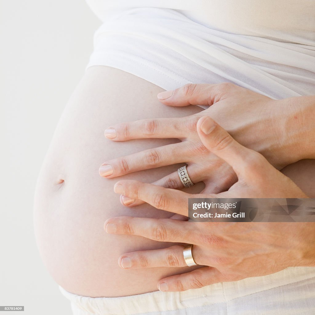Husband's and Wife's Hands on Pregnant Belly