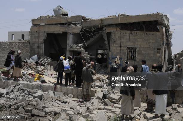 People gather around a heavily damaged building after Saudi-led coalition's air strikes over Arhab District of Sanaa, Yemen on August 23, 2017. At...