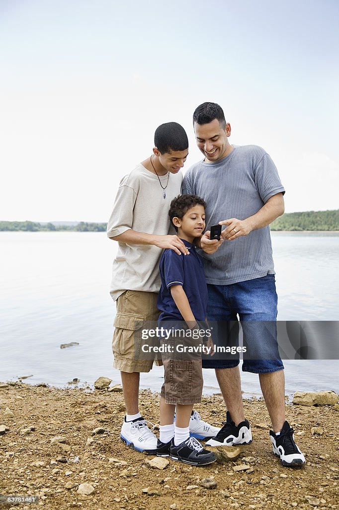 Father and Sons, by the Beach, Look at Cell Phone