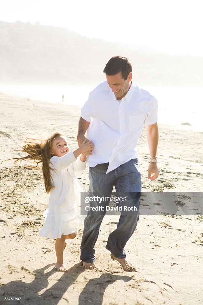 Dad and daughter runnng on the beach