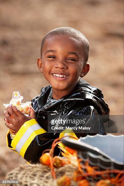 little boy in firefighter costume smiling. - boy fireman costume stock pictures, royalty-free photos & images