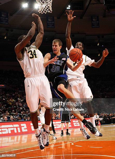 Jon Scheyer of the Duke Blue Devils goes to the basket between DeShawn Sims and Manny Harris of the Michigan Wolverines on November 21, 2008 at...