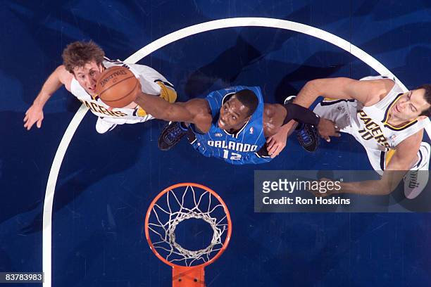 Dwight Howard of the Orlando Magic rebounds over Troy Murphy and Jeff Foster of the Indiana Pacers at Conseco Fieldhouse on November 21, 2008 in...