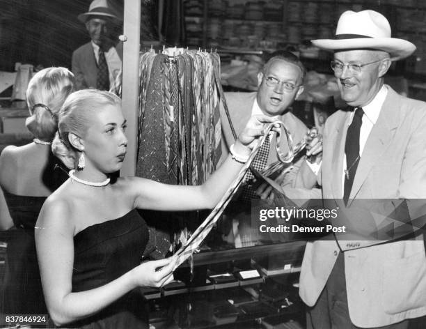 Pretty Bonnie Ann Shaw, who whistles and sings with Ted Weems' band at Elitch Gardens, pipes up a tune while she is absorbed in making a choice of a...