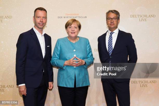 German Chancellor Angela Merkel poses with Handelsblatt chief editor Sven Afhüppe and Handelsblatt editor Gabor Steingart at "Germany Live: Where...