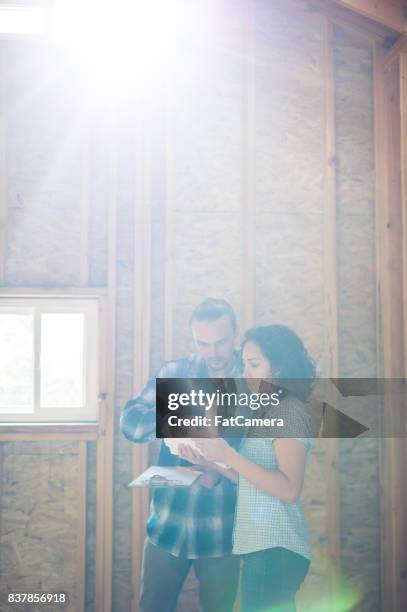 weibliche arbeitnehmer baupläne heraus die nächste phase des bauvorhabens auf einem klemmbrett - wohncontainer stock-fotos und bilder