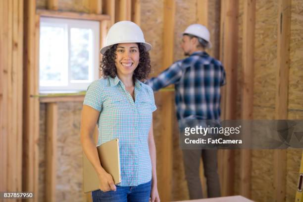 female construction worker plans out the next phase of the building project on a clipboard - temporary office stock pictures, royalty-free photos & images