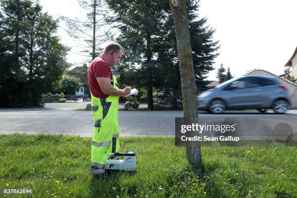 Worker uses a device to monitor the progress of a drill digging a horizontal hole in the ground below him during the installation of broadband fiber...