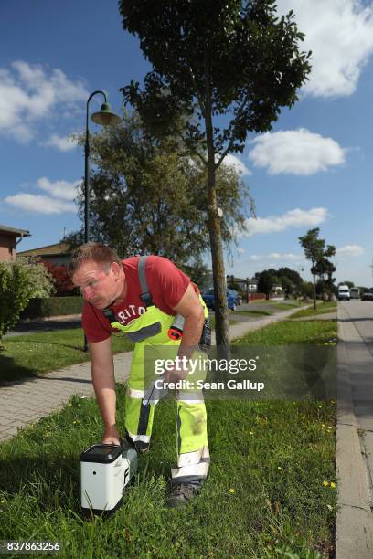 Worker uses a device to monitor the progress of a drill digging a horizontal hole in the ground below him during the installation of broadband fiber...