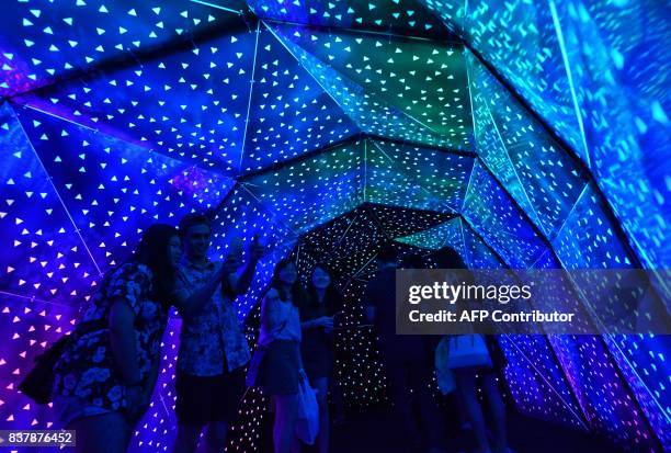 Visitors walk through a light tunnel titled 'Phospene' by Praxis Plus during a media preview of the Night Festival in Singapore on August 23, 2017....