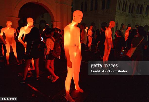 Visitors stand amongst illuminated mannequins titled 'The Standing Man' by French artists AADN during a media preview of the Night Festival in...