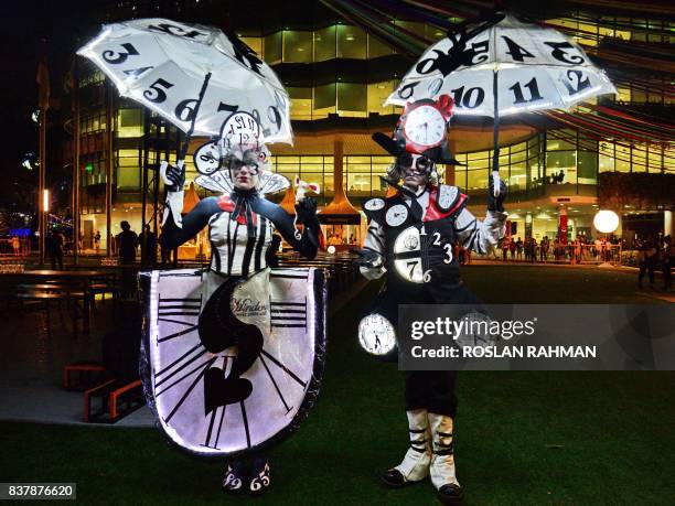 Australian performers illuminated with real clocks titled 'The Time Minder' attend a media preview of the Night Festival in Singapore on August 23,...