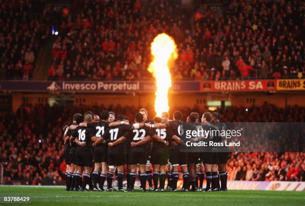 The All Blacks huddle on the pitch as pyrotechnics light the crowd prior to the start of the Invesco Perpetual rugby match between Wales and the New...