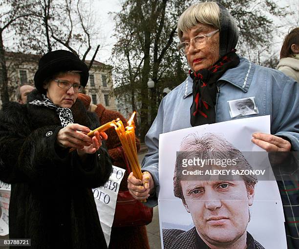 Women holding a poster of deceased former Russian spy Alexander Litvinenko light candles in his honor in Moscow on November 22, 2008. The man accused...