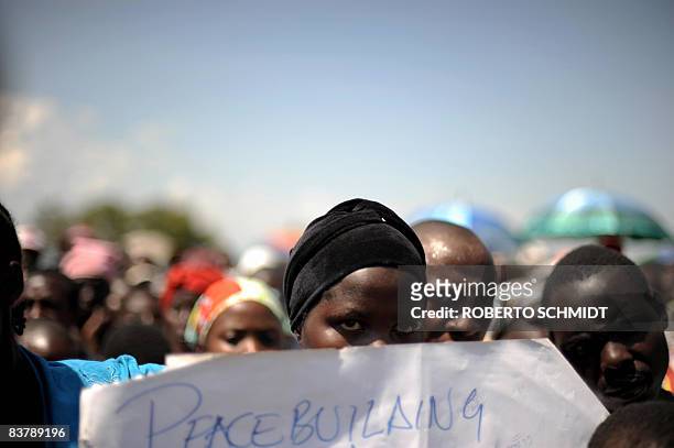 Woman in the crowd holds a peace sign as she joins others to listen to rebel leader Laurent Nkunda at the local stadium in the North Kivu town of...